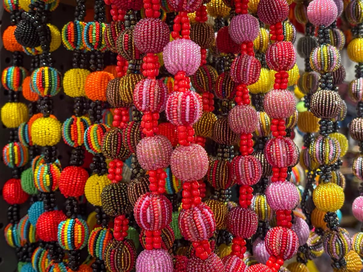 Strands of beaded baubles hanging close together in pink, red, yellow and black.