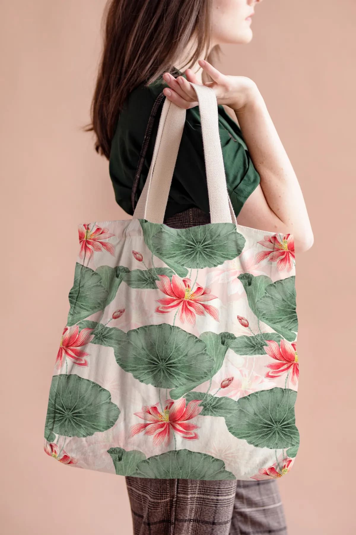 A cream canvas tote printed with pink lotus flowers and green lily pads, carried on the shoulder.